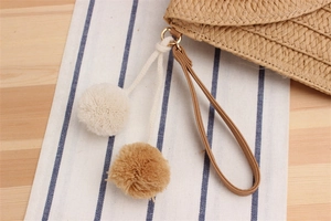 Détail du sac tressé en paille de papier avec bandoulière en cuir et pompon bicolore