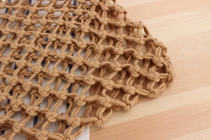 Detailed close-up of handmade hollow woven cotton rope bag on wood surface
