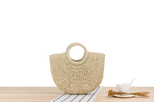 Detail of hand-woven beige paper rope bag featuring a circular handle and rustic cross-weave texture