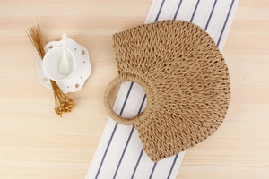 Detailed close-up of handmade semi-circular paper rope woven summer beach handbag on table
