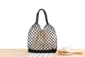 Macro detail of the black hand-woven mesh structure and fabric drawstring inner pouch