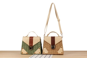 Detail of woven straw bags with leather trim, metal buckles and top handles in two colors