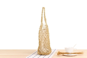 Detail of hand-woven gold metallic mesh tote bag with beige canvas drawstring liner
