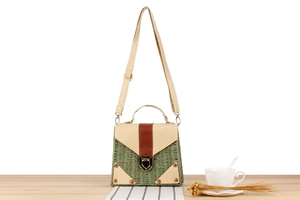 Close-up of green woven paper bag with leather flap and metal clasp on wooden table