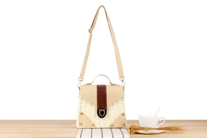 Detail of paper straw woven bag with leather trim and gold metal twist lock closure