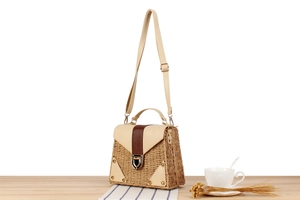 Detail of straw and leather patchwork bag with gold metal buckle and woven texture