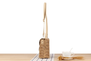 Detail of paper straw woven bag with adjustable leather strap on a rustic table