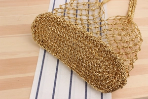 Close-up of golden woven mesh bag showing intricate crochet texture and solid base