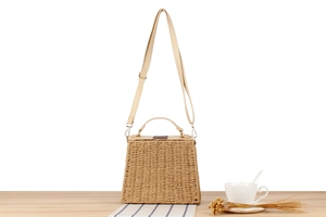 Detail of paper rope woven texture with light beige faux leather handle and gold hardware