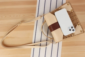 Detail of paper straw woven bag with leather flap and smartphone for scale reference