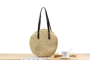 Vue détaillée du sac rond en paille tressée avec bandoulière marron et texture papier