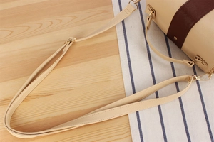 Detail of beige lychee grain leather bag with brown stripes and adjustable shoulder strap