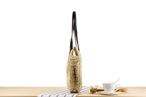 Détail d'un sac rond en paille tissé main montrant la texture et la fine bandoulière