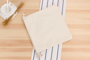 Detail of the woven drawstring canvas bag made of natural cotton on a wooden surface