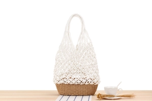Detail of handmade woven tote bag featuring white cotton crochet and straw base