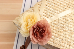 Detail of straw woven beach bag featuring 3D floral decorations and pearl accents