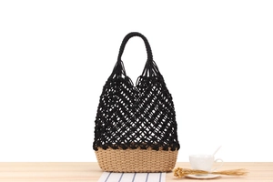 Detail of handmade macramé bag with black woven mesh and natural straw base