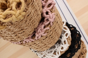 Close-up of woven straw beach bags featuring colorful braided rope trims in multiple colors