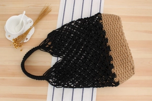 Detail of two-tone crochet and straw beach bag on a rustic wood and fabric background