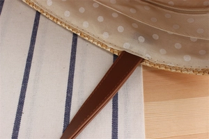 Macro detail of straw tote bag with beige polka dot lining and smooth metal zipper