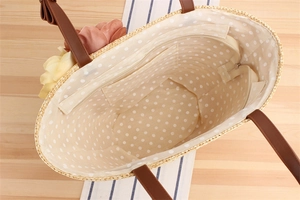 Macro view of woven straw tote bag interior with polka dot lining and zip pocket
