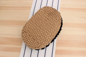 Detailed view of the hand-woven bottom featuring black lace trim on a straw beach bag