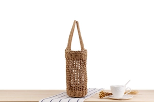 Detail of hand-woven hollow mesh tote bag on wooden table with rustic home decor
