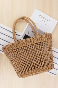 Detail of hollow woven beach bag with round handles on a wooden and striped background