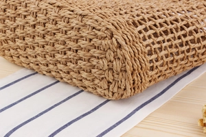 Close-up of handmade hollow woven straw bag with natural fiber texture on wood background