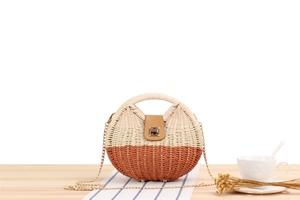 Dettaglio borsa rotonda in paglia intrecciata bicolore con catena dorata sottile