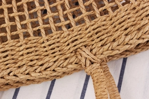 Close-up of the woven hollow straw handbag handle with reinforced stitching details