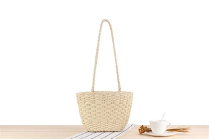 Close-up of beige paper rope woven shoulder bag texture on a wooden table