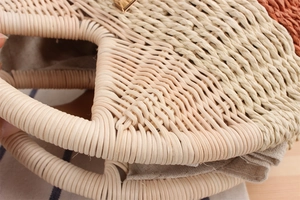 Dettaglio della borsa in paglia intrecciata a mano con strati colorati e chiusura dorata