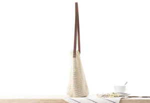 Détail du sac bandoulière en paille tressée avec lanières en cuir marron et rivets