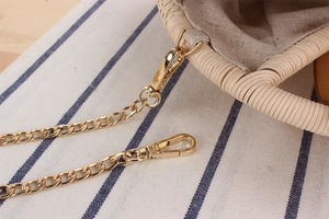 Dettaglio della trama della borsa in paglia intrecciata con catena in metallo dorato