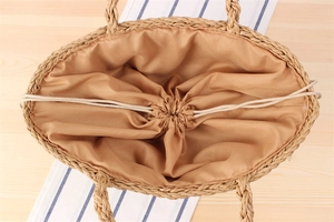 Detailed close-up of woven paper straw tote bag with fabric lining and drawstring closure