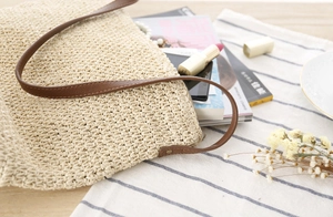 Détail de la texture en papier tressé du sac et poignée en cuir marron avec rivets