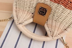 Dettaglio borsa in paglia intrecciata bicolore con chiusura in metallo e catena