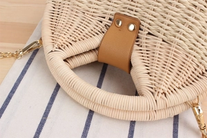 Dettaglio borsa rotonda in paglia intrecciata con fibbia in pelle e catena dorata