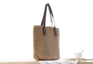 Détail du sac cabas en paille tissée avec anses en cuir marron et rivets
