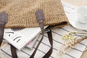 Détail du sac cabas en paille tressée avec anses en cuir marron et intérieur spacieux
