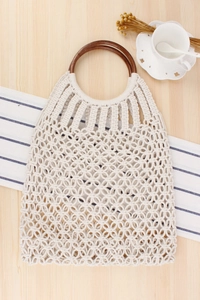 Detail of handmade cream cotton rope woven bag with rustic brown wood ring handles
