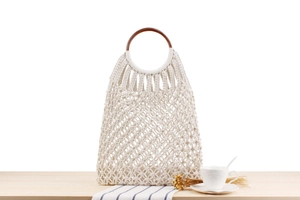 Detail view of cream cotton woven bag with dark brown round wooden handle for beach vacation