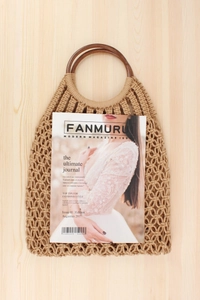 Detail of hand-woven cotton net bag with round wooden handles on a light wood background