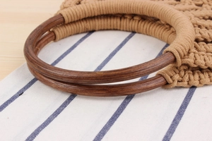 Detail of woven cotton rope bag featuring smooth circular wooden handles and boho texture