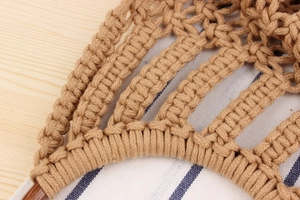 Close-up of handmade cotton rope weave and wooden handle on a beige beach tote bag