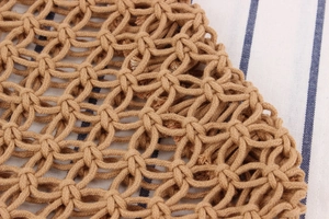 Detailed macro view of brown hand-woven mesh texture on rustic cotton rope beach bag
