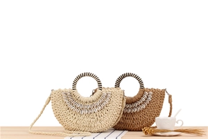 Detail of woven straw crescent bags with natural shells and striped ring handles for vacation