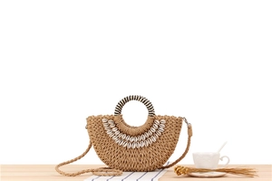 Detail of semicircular straw bag with shell decor and striped woven round handles