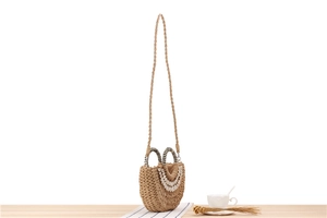 Detailed view of woven straw bag with decorative white shells and striped handles